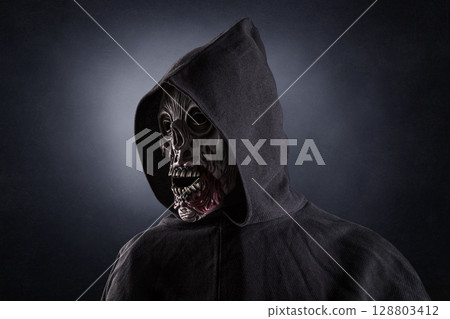 Portrait of a zombie with hooded cape over dark misty background Portrait of a zombie with hooded cape over dark misty background 128803412
