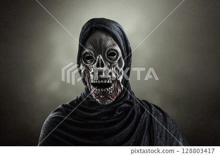 Portrait of a zombie with hooded cape over dark misty background 128803417