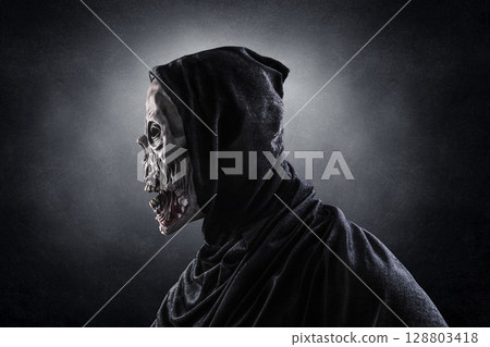 Portrait of a zombie with hooded cape over dark misty background Portrait of a zombie with hooded cape over dark misty background 128803418