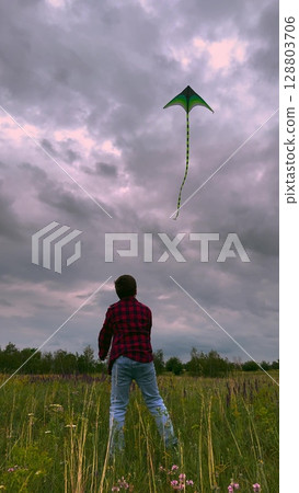 child playing kite sky background, children play outdoor nature, Dramatic Sky and Playful Spirit, Kite Flight in a Wild Meadow, Red Plaid Shirt Adventure, The Wonder of Flight, Freedom on the Open 128803706