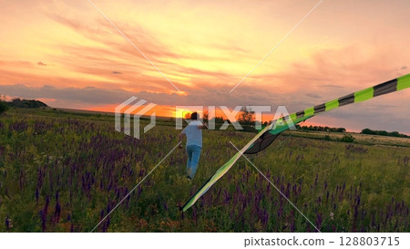 child boy running kite sunset, kid childhood dream happy family,silhouette outdoor play, Running through wildflower meadow, Sun setting on the horizon, Kid holding kite string, Vibrant sunset colors 128803715