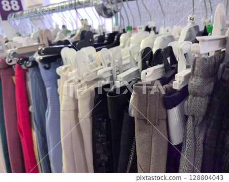 Colorful assortment of pants hanging on display in a trendy boutique store Colorful assortment of pants hanging on display in a trendy boutique store 128804043