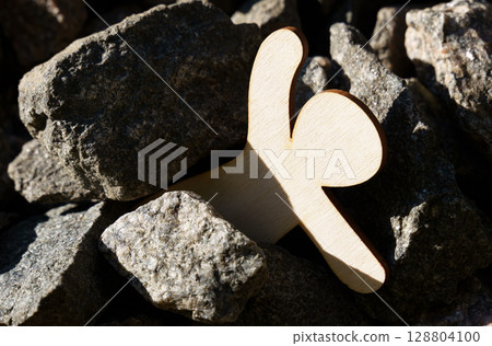Wooden figure reaching for help amidst stones in outdoor setting 128804100