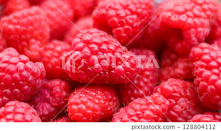 A vibrant and inviting close-up of a pile of fresh, ripe red raspberries, showcasing their delicate texture and rich color. 128804112