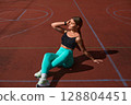 Fit woman exercising outdoors on a sunny day, showcasing strength and determination while enjoying a healthy lifestyle and fitness routine. Workout concept 128804451