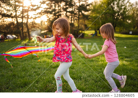 Joyful children flying a colorful kite in a sunny park 128804605