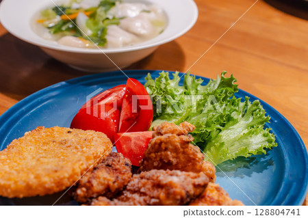 Dinner of vegetable-packed dumpling soup and fried chicken plate 128804741