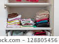 Folded children's clothes in the closet, storage of children's clothes. 128805456