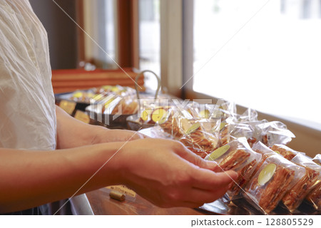 A woman picking up baked goods at a pastry shop 128805529