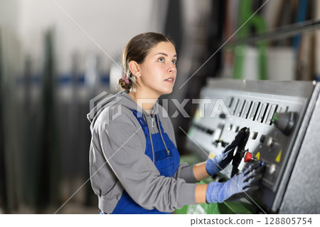 Young woman operates control panel in factory Young woman operates control panel in factory 128805754