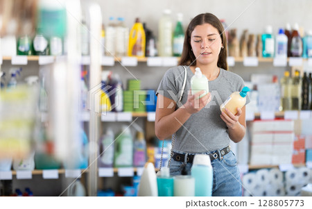 Young woman buyer chooses liquid soap in store 128805773