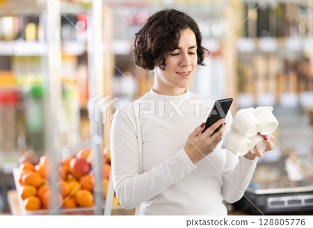 Adult woman scanning qr code for yogurt Adult woman scanning qr code for yogurt 128805776
