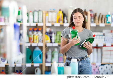 Female customer comparing dishwashing liquids in household store Female customer comparing dishwashing liquids in household store 128805780