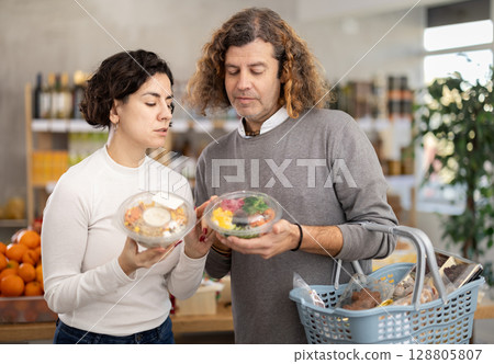 In store, spouses near counter are looking at poke salad In store, spouses near counter are looking at poke salad 128805807