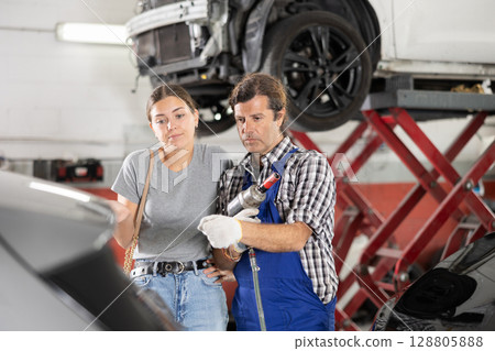 Worried woman talks about the problems of her car to an auto mechanic at car service center Worried woman talks about the problems of her car to an auto mechanic at car service center 128805888