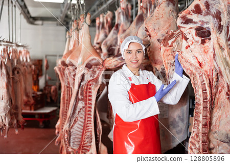 Female butcher showing beef chunk in meat storage 128805896