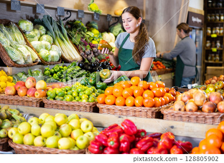 Young woman selling bell peppers in shop 128805902