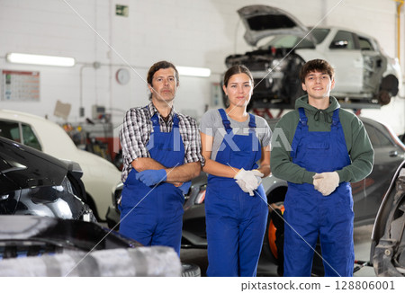 Portrait of team of auto mechanics near cars in car service center 128806001