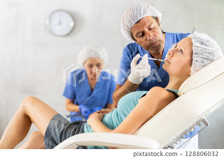 Woman applying rejuvenating treatments by male doctor. 128806032