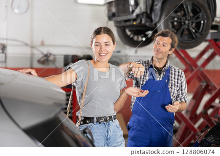 Male mechanic giving car keys to woman client Male mechanic giving car keys to woman client 128806074