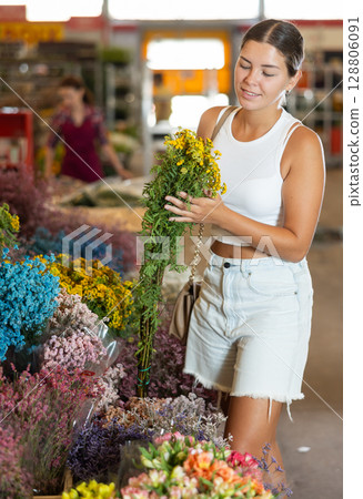 Young girl holding bouquet of dry flowers in large plants market 128806091