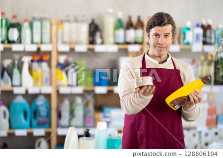 Man seller stands in trading hall of household store, offer goods Man seller stands in trading hall of household store, offer goods 128806104