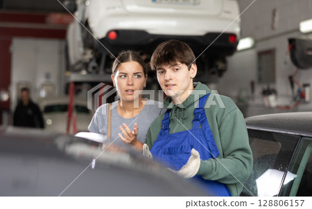 Interested female client talking to young auto mechanic 128806157