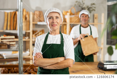 Elderly woman seller posing in bakery Elderly woman seller posing in bakery 128806174