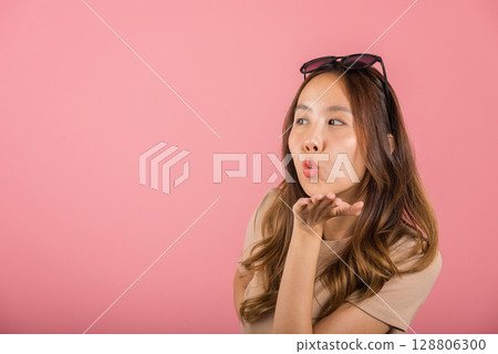 Asian happy portrait beautiful cute young woman teen standing blowing kiss air something on palm hands expresses her love looking to camera studio shot isolated on pink background with copy space Asian happy portrait beautiful cute young woman teen standing blowing kiss air something on palm hands expresses her love looking to camera studio shot isolated on pink background with copy space 128806300