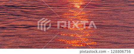 The water surface and the path of light sparkling in the light of the setting sun 128806756