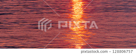 The water surface and the path of light sparkling in the light of the setting sun 128806757