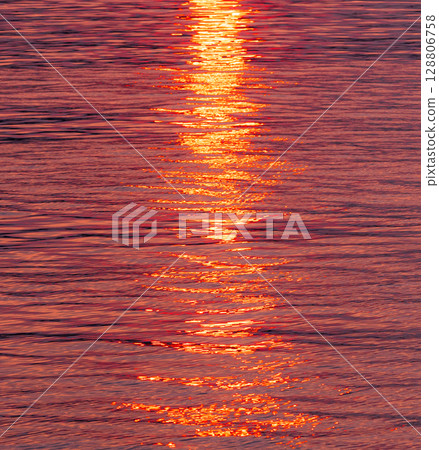 The water surface and the path of light sparkling in the light of the setting sun 128806758