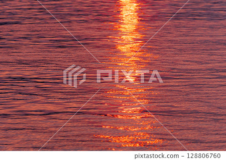 The water surface and the path of light sparkling in the light of the setting sun 128806760