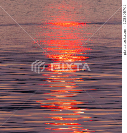 The water surface and the path of light sparkling in the light of the setting sun 128806762