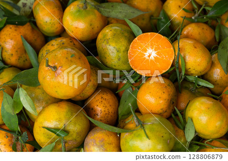 Fresh mandarins with leaves showing a half cut fruit exposing its juicy interior 128806879