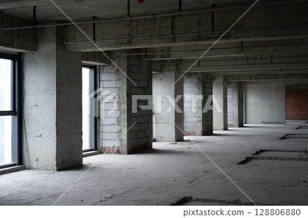 Unfinished concrete and brick industrial building interior showing windows and pillars Unfinished concrete and brick industrial building interior showing windows and pillars 128806880