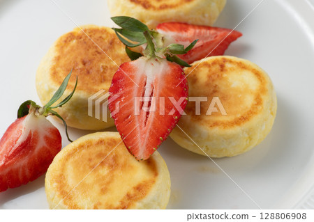Cheesecakes with fresh strawberries lying on white plate 128806908