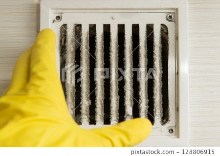 Cleaning technician wearing gloves checking dirty ventilation grille Cleaning technician wearing gloves checking dirty ventilation grille 128806915