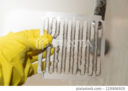 Technician showing dirty ventilation grill covered with dust 128806920