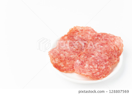 Sliced salami on a plate on a white background 128807569