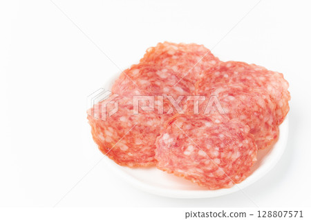 Sliced salami on a plate on a white background Sliced salami on a plate on a white background 128807571