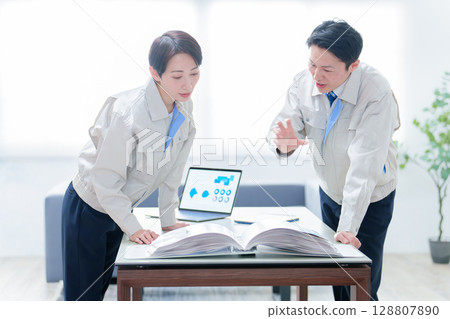 Workers checking a catalog and holding a meeting Workers checking a catalog and holding a meeting 128807890