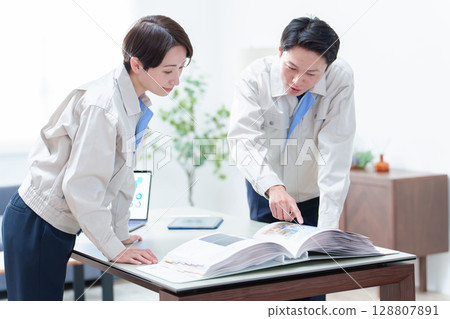 Workers checking a catalog and holding a meeting 128807891
