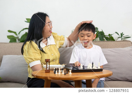 Joyful Interaction: Mother and Son Playing Chess Together 128807931