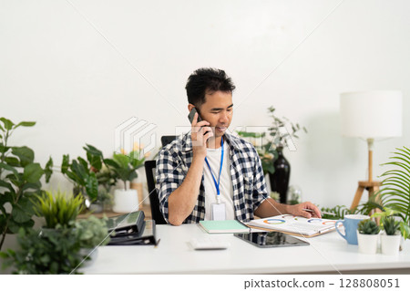Business communication. Young man talking on phone in modern office. Business communication. Young man talking on phone in modern office. 128808051