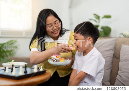 Nurturing Bond. Grandmother Sharing Cupcake with Child After Chess Nurturing Bond. Grandmother Sharing Cupcake with Child After Chess 128808053