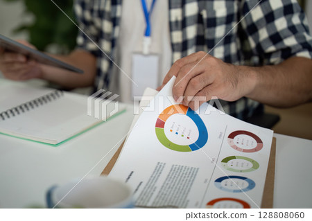 Data Analysis. Professional reviewing colorful charts and graphs in a modern office. 128808060