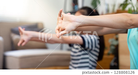 Mother and daughter practicing stretching exercises at home Mother and daughter practicing stretching exercises at home 128808126