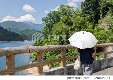 盛夏的八木澤水壩：撐著陽傘眺望奧利根湖的女子 128808251