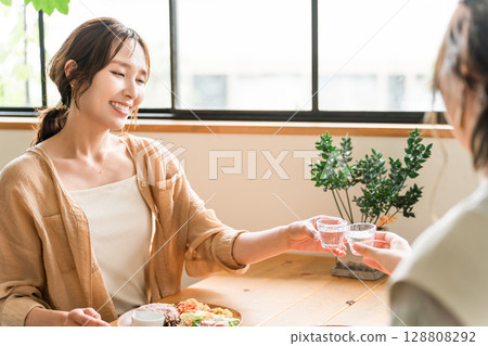 在女孩聚會上，年輕的亞洲女性用冷清酒杯喝日本清酒 128808292
